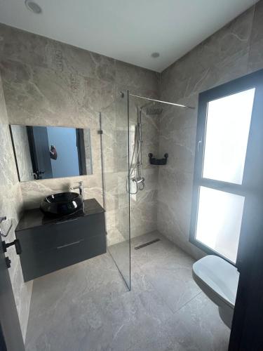 a bathroom with a shower and a toilet and a mirror at Villa blanca in Al Maqārisah