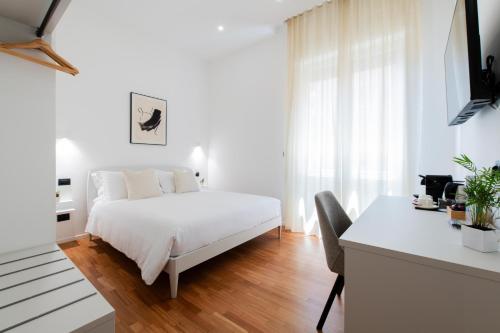 a white bedroom with a bed and a desk at Lumen Boutique Stay in Naples