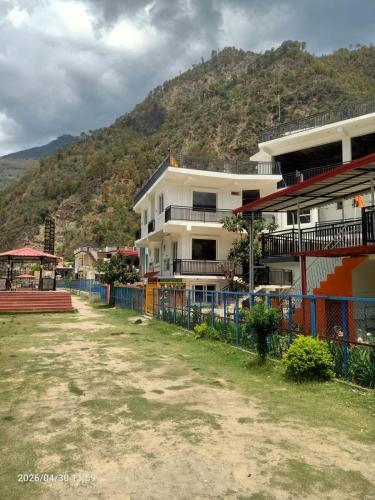 a building with a fence in front of a mountain at Virasat in Uttarkāshi