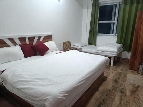 a bedroom with a large white bed and a window at Virasat in Uttarkāshi