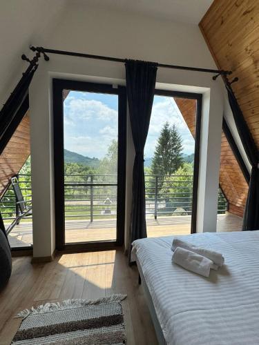 a bedroom with a bed and a large window at A-frame Noa Cabin in Teşila