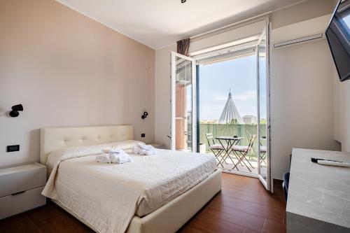 a white bedroom with a bed and a balcony at Panoramic Rooms in Syracuse