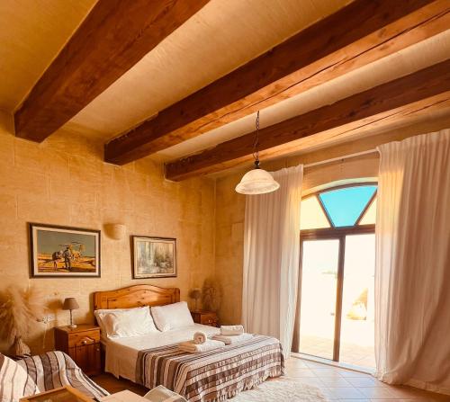 a bedroom with a bed and a large window at Narcisa Farmhouse B&B in Nadur