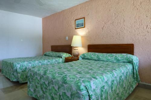 a hotel room with two beds and a lamp at Hotel Aristos Cuernavaca in Cuernavaca