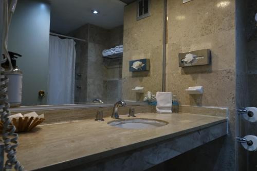 a bathroom with a sink and a large mirror at Hotel Aristos Cuernavaca in Cuernavaca