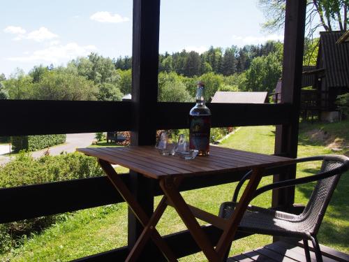 a table with a bottle and glasses on a porch at Kemp Prachovská osma in Libuň