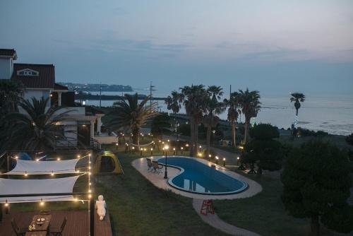 a view of a resort with a swimming pool at night at Jeju Its Hill Pension in Jeju