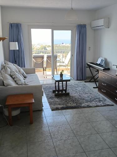 a living room with a couch and a table at Two BR Sea View with Balcony and Pool Paphos in Khlorakas