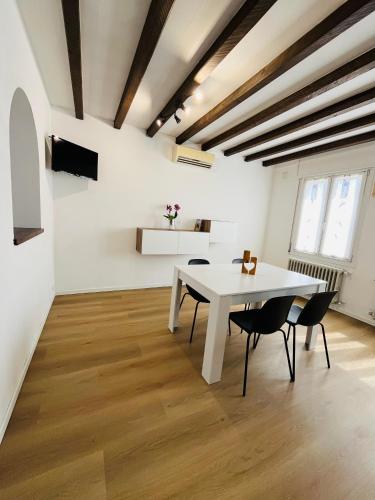 a white dining room with a white table and chairs at La casa di Teo in Cappella Maggiore