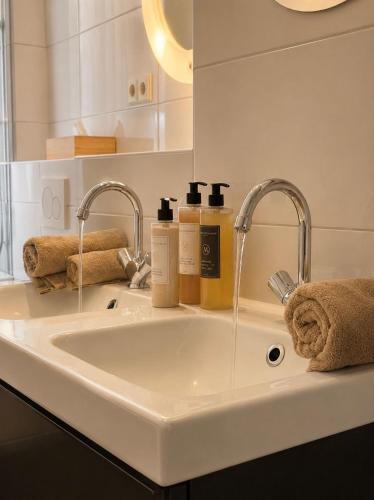 ein weißes Badezimmerwaschbecken mit zwei Wasserhähnen und Handtüchern. in der Unterkunft La Rive in Enschede