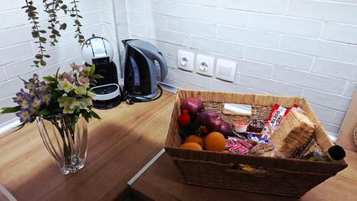 a basket of fruit on a table with a vase of flowers at Veronica's House in Zagora