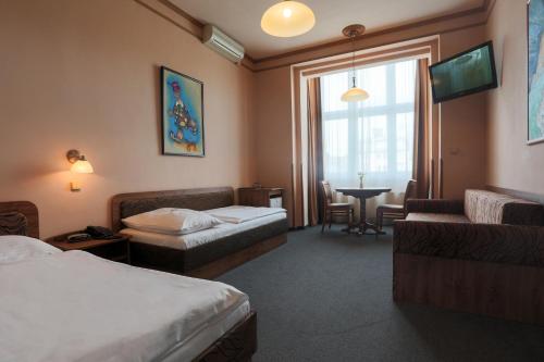 a hotel room with two beds and a table at Hotel Victoria in Plzeň