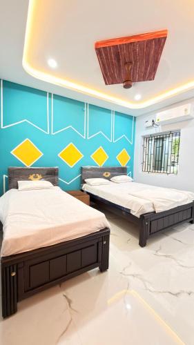 two beds in a room with blue and yellow wall at Ramnath Residency in Rāmeswaram