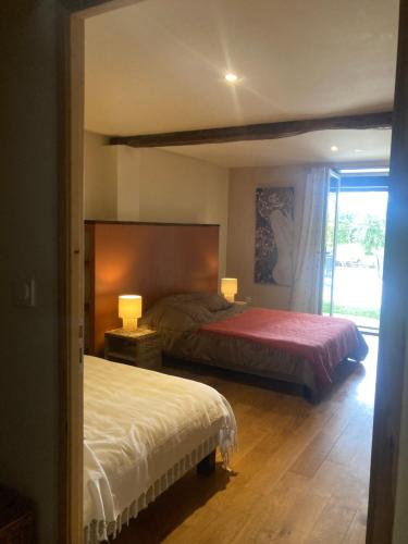 a bedroom with two beds and two lamps and a window at Appartement à colombages indépendant avec piscine partagée avec le proprietaire in Ponsan-Soubiran