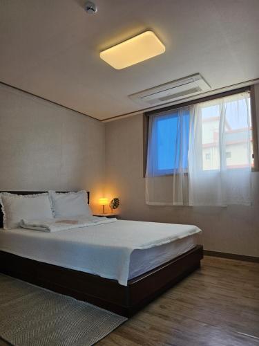 a bedroom with a large bed with a window at Seongsan Star Pension in Seogwipo