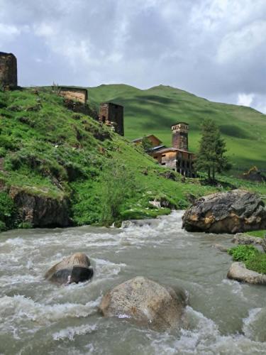 a river with rocks and buildings on a hill at ENO Grand Mountain Escape in Murkmeli