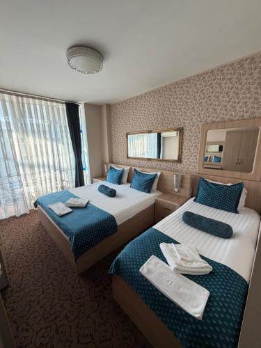 a hotel room with two beds and a mirror at Hotel Pejton in Prishtinë