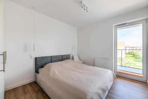 a white bedroom with a bed and a window at Helskafoka2 in Hel