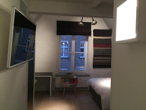 een kleine slaapkamer met een bed en een raam bij B-Square in Brugge