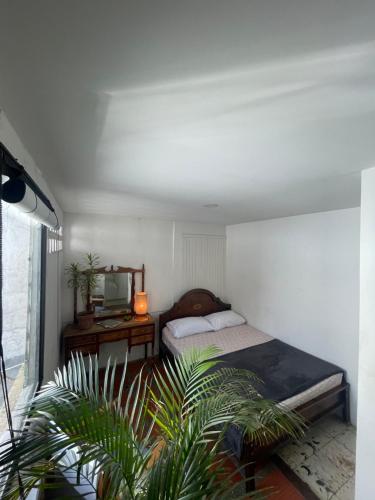 a bedroom with a bed and a desk and a television at Hostal Casa Las Tías in Medellín