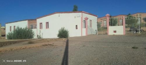 a white building with a gate on the side of it at Camping Imdghas in Tilmi