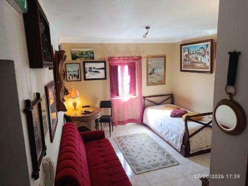 a living room with a red couch and a bed at Vintage Apartment in Vila Nova de Milfontes