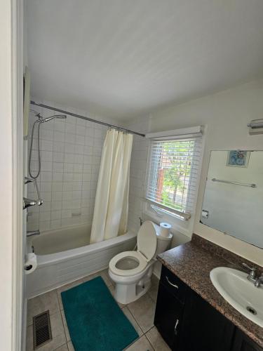 a bathroom with a toilet and a tub and a sink at Cozy and comfortable home - Living room and Kitchen is shared in Pickering