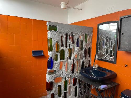 a bathroom with a sink and a wall of bottles at Hostal Casa Las Tías in Medellín