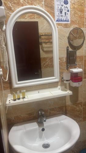 a bathroom sink with a mirror and a tv above it at فندق منازل الراشدين in Az Zahrāʼ