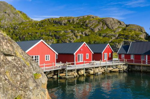 a row of red houses on a dock with a mountain at Statles Rorbu- og Konferansesenter AS in Leknes