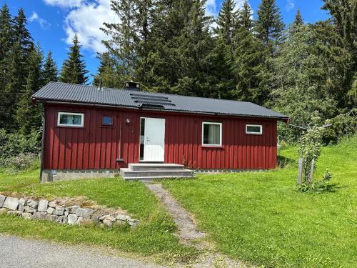a red cabin in a field with trees at Cabin with great view close to town and ski area in Lillehammer