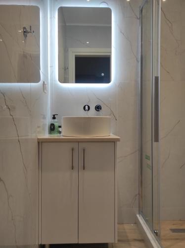 a white bathroom with a sink and a mirror at Katerina Studios in Paleokastritsa