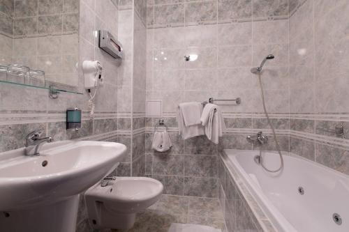 a bathroom with a sink, toilet and bathtub at Hotel Victoria in Pilsen