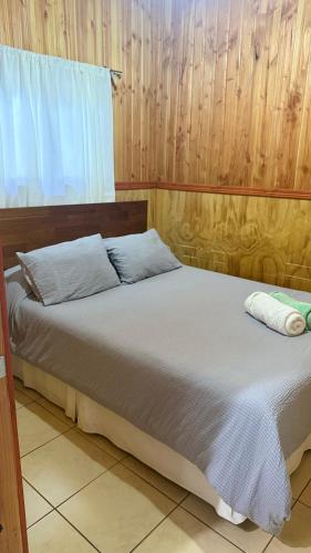 a bed with two pillows on it in a room at Cabañas Loncoche Puerta del Sol in Loncoche