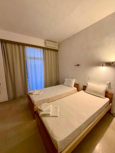 zwei Betten in einem Zimmer mit Fenster in der Unterkunft Nostos Mare in Preveza