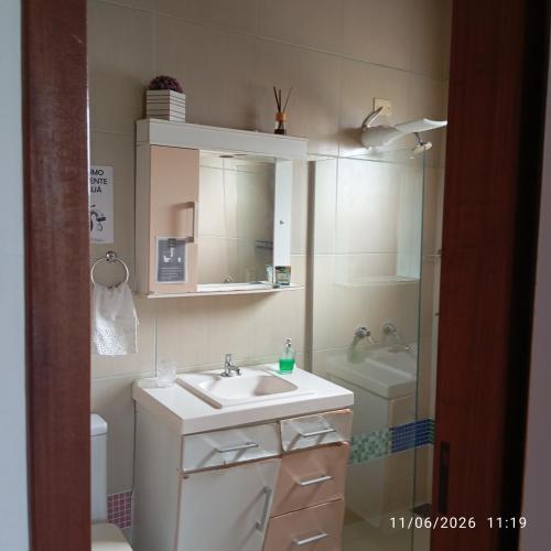 a bathroom with a sink and a toilet and a mirror at Singela Casa em Chapada dos Guimarães in Chapada dos Guimarães