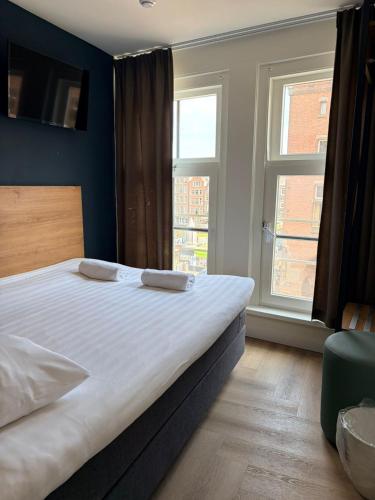 a bedroom with a large bed and two windows at Hotel Continental Amsterdam in Amsterdam