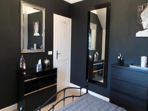 a bedroom with black walls and a mirror at Le Montaigne in Saint-Alvère