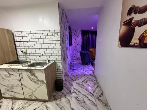 ein Badezimmer mit Waschbecken und einer lila Decke in der Unterkunft Desami Hotel in Omole