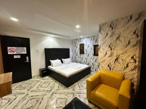 ein Schlafzimmer mit einem Bett und einem gelben Stuhl in der Unterkunft Desami Hotel in Omole
