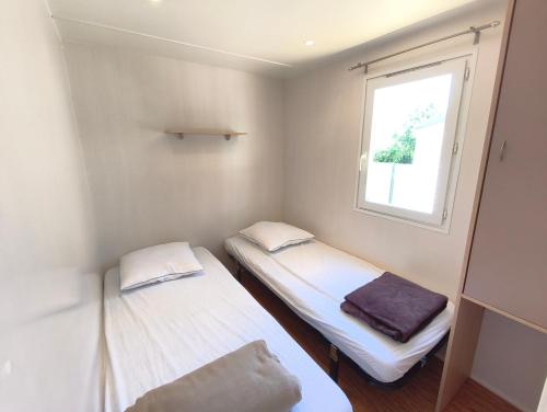 two beds in a small room with a window at l'instant provence in Pradons