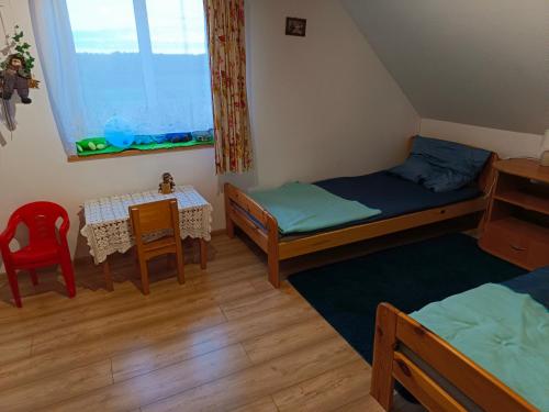 a room with two beds and a table and chairs at Zacisze pod lasem in Ruciane-Nida