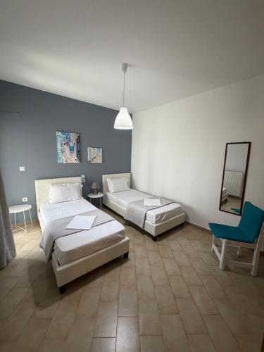 a bedroom with two beds and a mirror and a chair at Elenas Apartments in Plataria