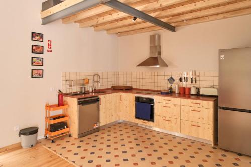 a kitchen with wooden cabinets and a stainless steel refrigerator at Manas Slowliving - Santiago in Santiago do Cacém