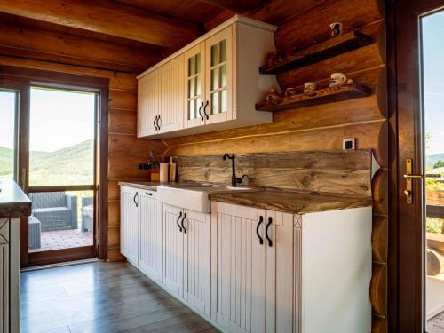 a kitchen with white cabinets and wood walls at Chalet Val d'Or in Nová Baňa