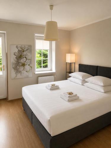 a bedroom with a large white bed with two towels on it at Villa Jeziorki in Warsaw