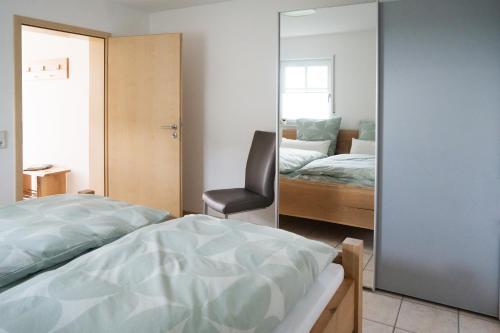 a bedroom with a mirror and a bed and a chair at Ferienwohnung Hansen in Welschbillig