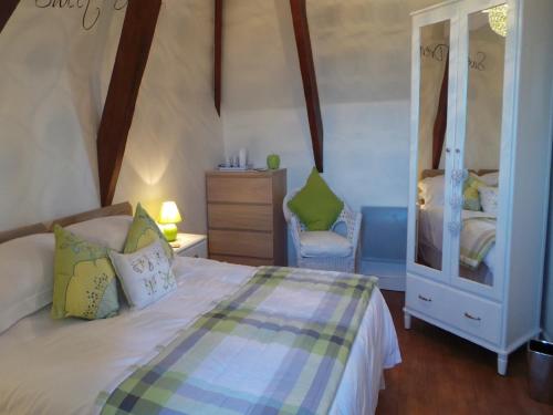 une chambre avec un lit, une commode et un miroir dans l'établissement Le Montaigne, à Saint-Alvère