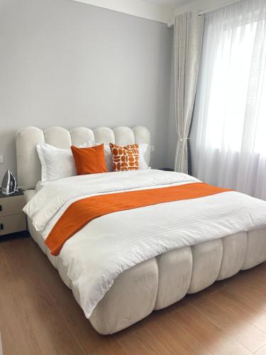 a bedroom with a large bed with orange and white pillows at Cozy Nest in Marimbeti