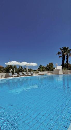 a large blue swimming pool with chairs and umbrellas at Abela Family Hotel in Argassi